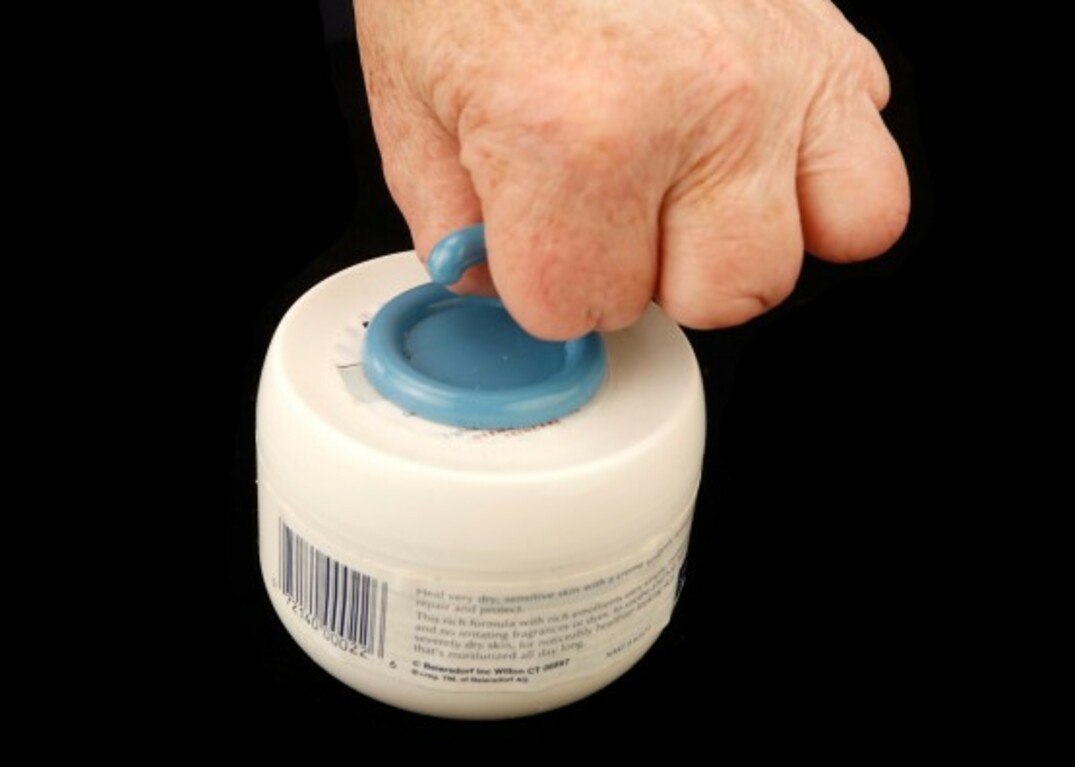 Cindy's hand uses a peel-and-stick hook to open a jar of cold cream.